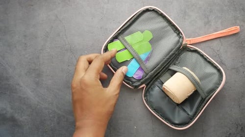 Hand removes bandage from first aid kit
