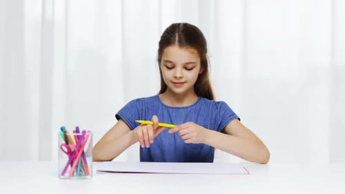Young Girl Draws with Yellow Marker at Table