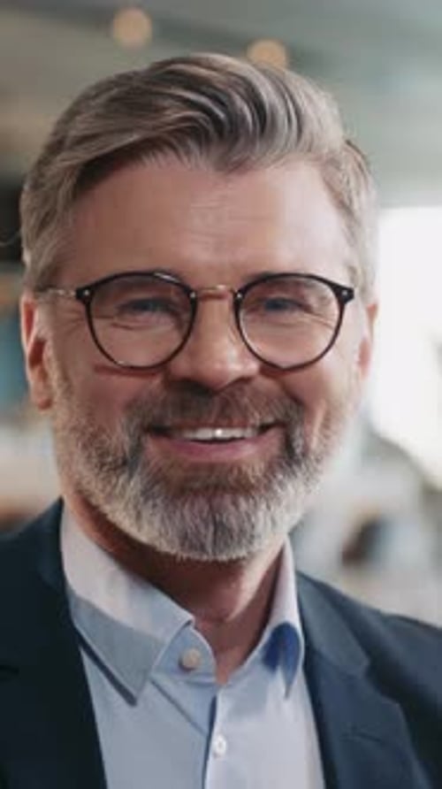 Portrait d'un séduisant homme d'affaires caucasien souriant dans des lunettes regardant la caméra en gros plan