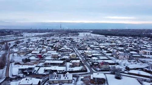 Aerial wide view of Snowed covered small city in Latvia with sunset sky orbiting