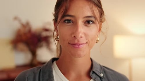 Close up, young smiling woman looking at camera standing in living room