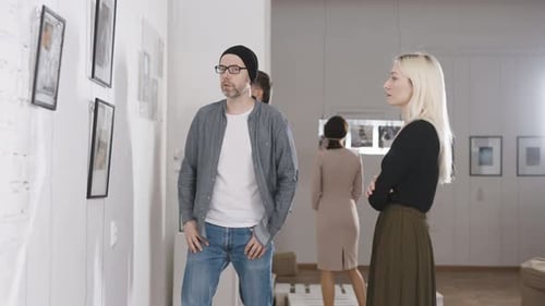 Men and Women in an Art Gallery Inspect the Abstract Works of Contemporary Artists