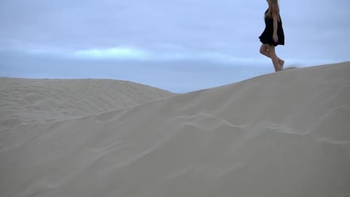 Beautiful style of woman in black dress walking bare foot on sand dune