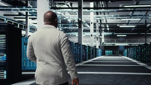 Admin Walking in High Tech Data Center Facility with Rows of Supercomputers