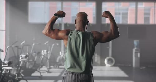 Exercise, black man and back view of flexing biceps, bodybuilder and fitness in gym