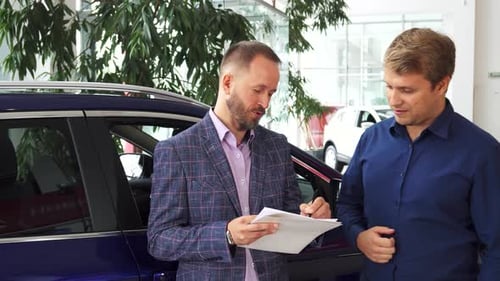 Man Signing Car Contract at Dealership Showroom