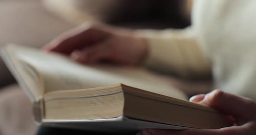Unrecognizable Young Woman Reading Book in Cozy Living Room Turning Page Learning Studying Education