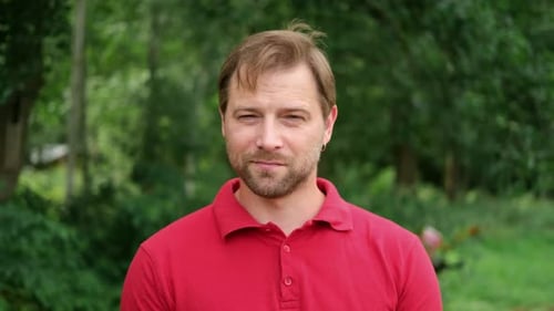 Man in a Red Shirt Outdoors Stares at Camera