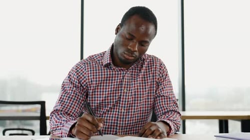African American Student Sits in Library Prepare for Exam and Making Notes in Notebook