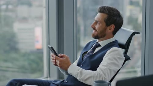 Satisfied Entrepreneur Watching Phone Receiving Sms Sitting at Office in Elegant Suit