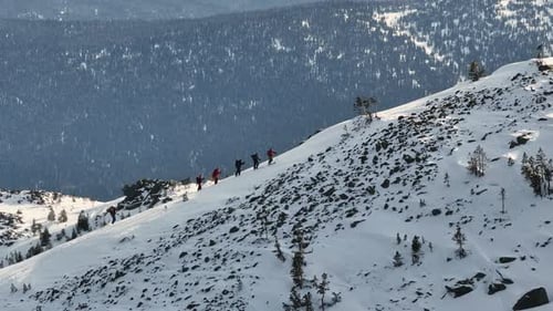 Gruppe von Bergsteigern besteigt im Winter den verschneiten Bergrücken