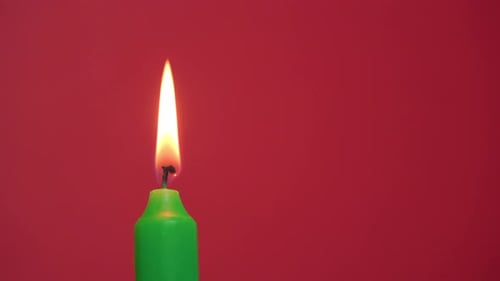 Green Candle Alight on Red Background