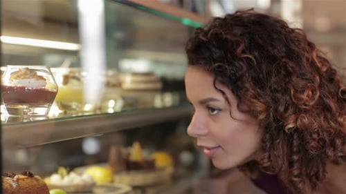 Woman Looks at Delicious Desserts in Bakery Case