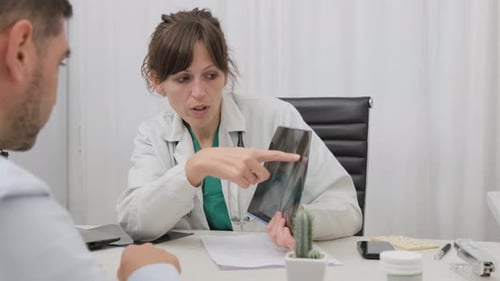 Female Medical Doctor Explaining X-ray Result To Male Patient In The Clinic. medium shot