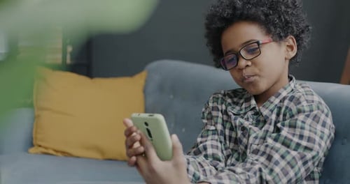 Boy on Couch Using Smartphone Indoors