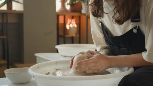 Woman Shaping Piece of Clay on Potters Wheel in workshop