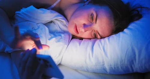 Woman Lying in Bed Using Mobile Phone at Night