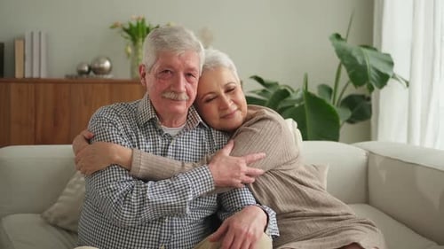Loving Senior Couple Embrace on Sofa