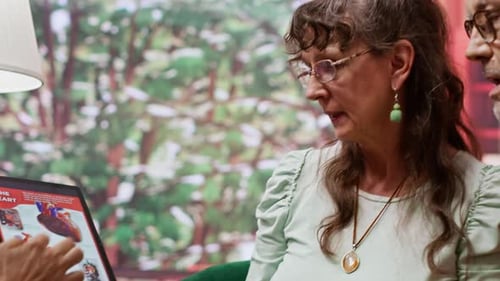 Adults Discussing Heart Diagram on Tablet Indoors