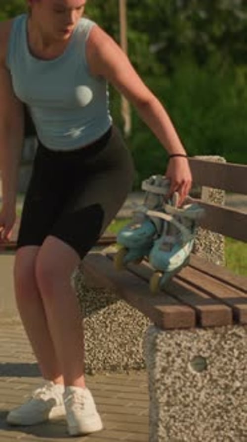 Young Lady Placing Roller Skates on Wooden Park Bench in Sunny Park Setting