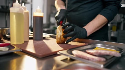 Closeup in a Professional Kitchen of a Chef's Hands Cutting Burger Bun in Half