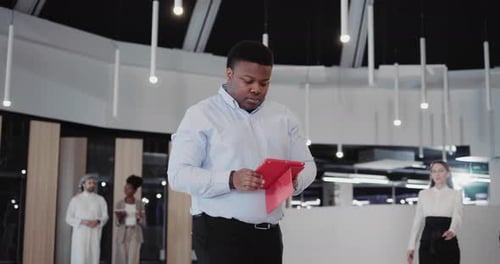 Black Young Office Manager Heading to Cabinet Using Tablet Application Computer Managing Business