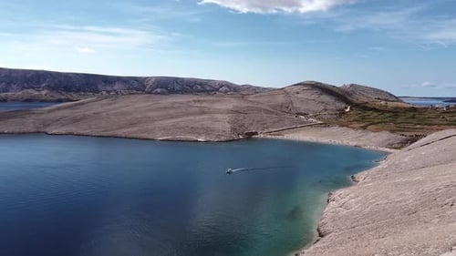 Drone flight near rocky mountains with the boat on the sea.