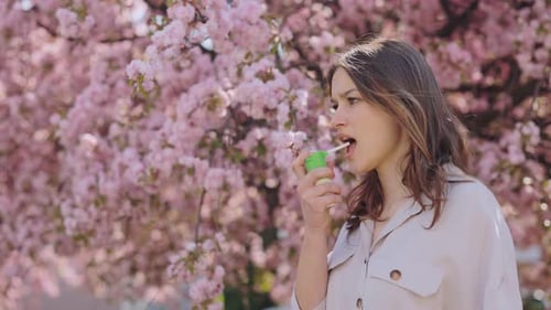 Femme allergique utilisant un inhalateur pendant la floraison printanière