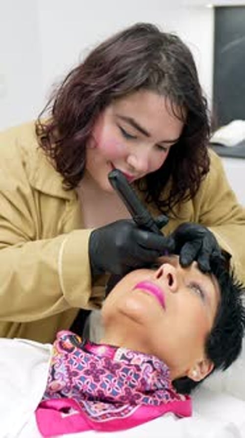 Professional beautician performing permanent eyeliner makeup procedure