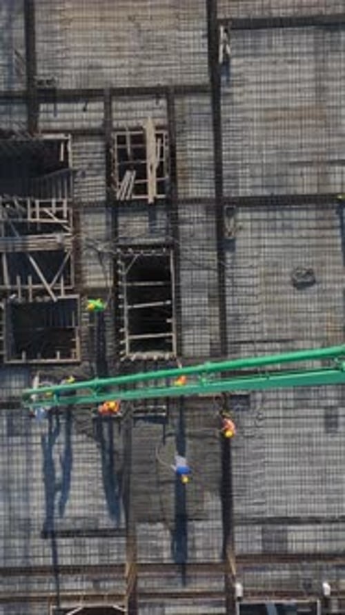 Vertical Video of Engineers Reviewing Plans While Workers and a Crane Build a Residential Project