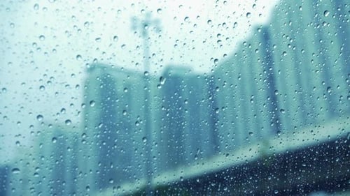 Raindrops On Glass Surface Window With Blurry Cityscape Background - close up