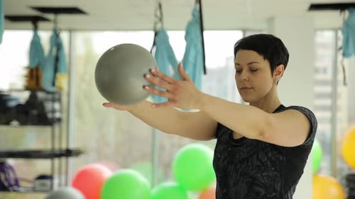 Woman Doing Exercise with Gray Ball in Gym
