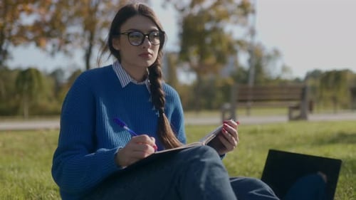 Young Student Girl Studying Outdoors in an Autumn Park