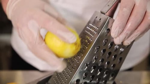 Hands Grating Fresh Lemon Zest with Metal Grater