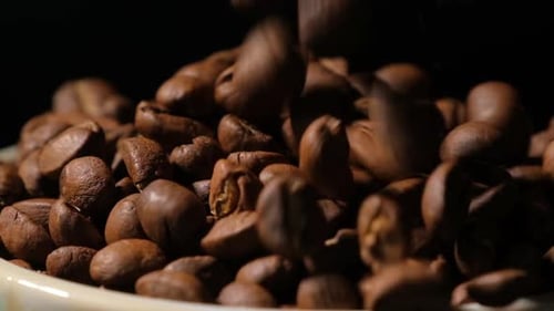 Zeitlupe fallender gerösteter Kaffeebohnen. Bio-Kaffeesamen.