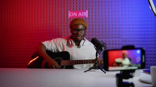 Young Adult Musician Playing Guitar, Recording a Broadcast