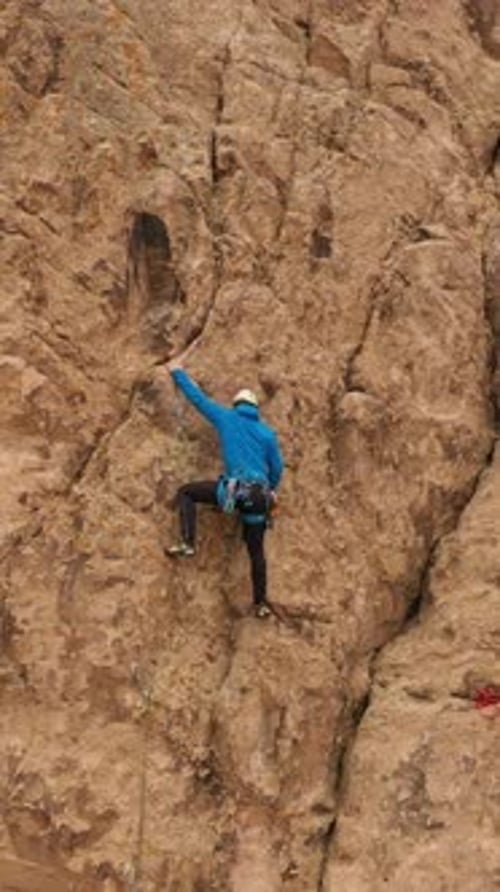 Man Climber Rock Climbing Cliffs in Tamgaly Tas Kazakhstan Aerial View Vertical Video