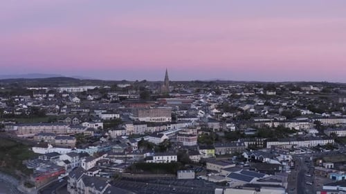 Pink sky dawn aerial rises over coastal town of Tramore, Ireland