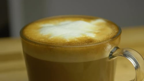 Slow shallow focus slide shot of Cup of hot Cappuccino on wooden table