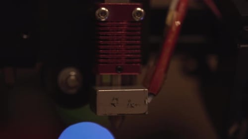 3D printer nozzle extruder hotend with lights of technology flashing in the background