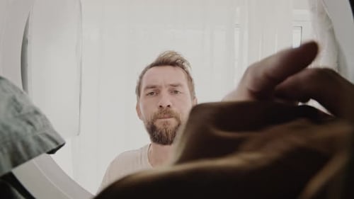 Man Pulls Laundry from Washing Machine Close Up