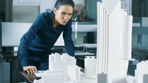 Female Architectural Designer Works on a Model of a City District with Buildings, Parks and It's Ow
