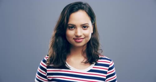 A cheerful young woman posing against a grey background