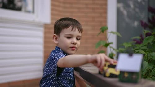 Child Plays with Toy Cars on Suburban Porch