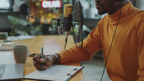 Man Recording Podcast in Studio Taking Notes