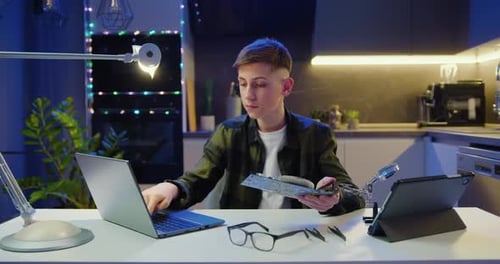 Escolar adolescente usando una computadora portátil y sosteniendo una placa de computadora en sus manos e instrucciones de lectura