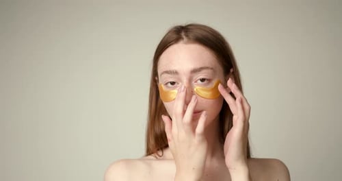 Woman Applies Gold Eye Masks for Beauty Treatment