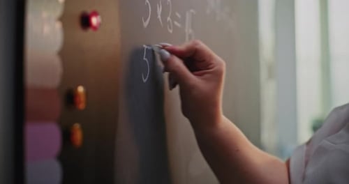 Female Teacher Writing on the Chalkboard Teaching Primary School Students to Solve Math Problems