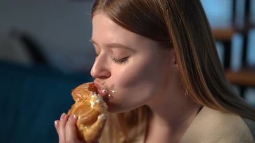 Woman Indulges in Cream Pastry in Close-Up