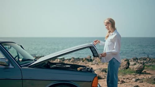 Girl Driver Opening Hood Retro Automobile at Ocean Shore Woman Looking Engine